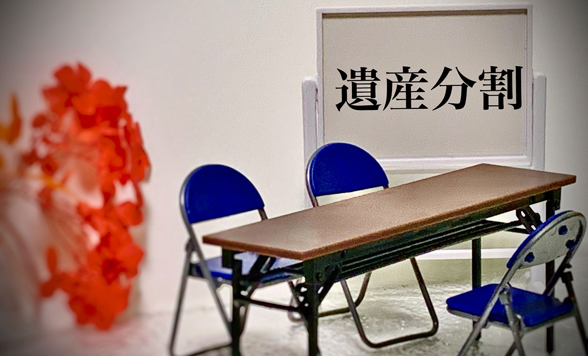 「遺産分割」と書かれたホワイトボードの前に、細長い会議用テーブルと3つの青いパイプ椅子がセットされている