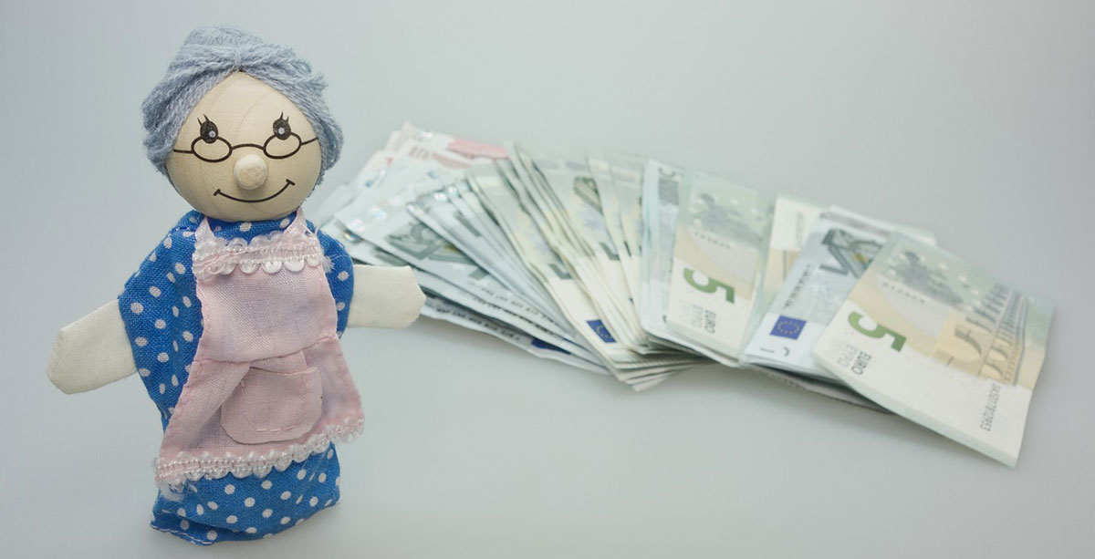 数十枚のユーロ紙幣を背景にした可愛らしいおばあさんの人形